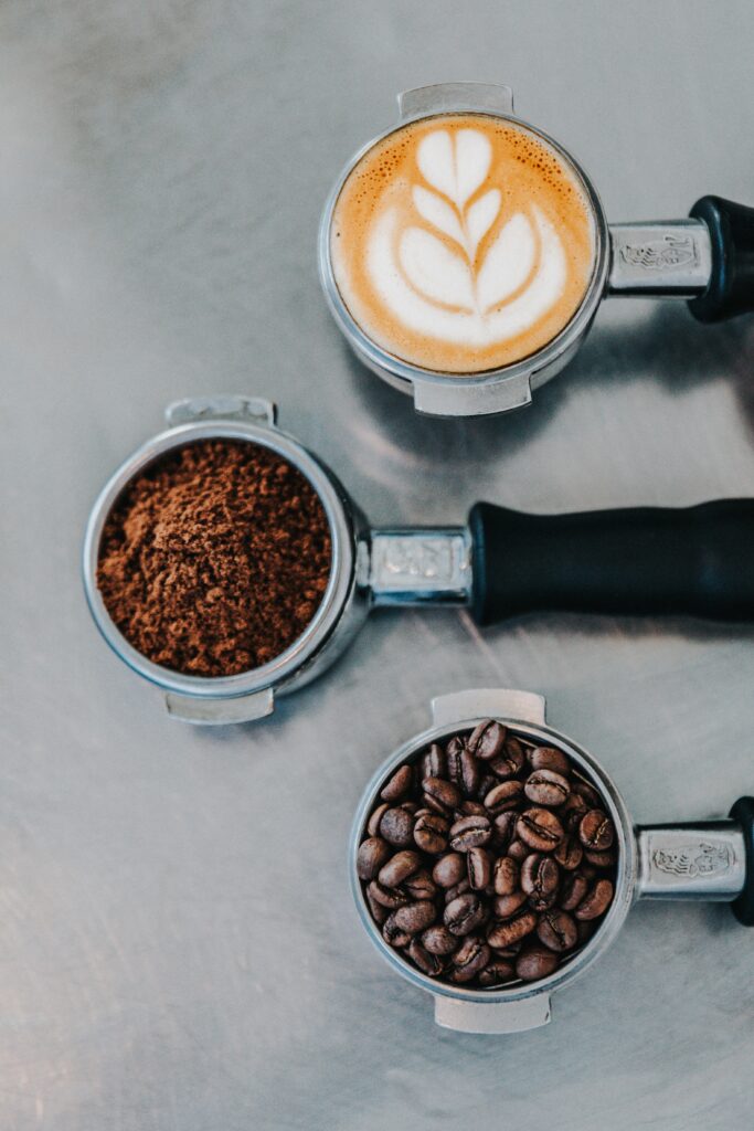 3 handtag till espressomaskin, en innehållande färdigrostade kaffebönor, en med malt kaffe och en med hjärtformat skum likt en cappucino.